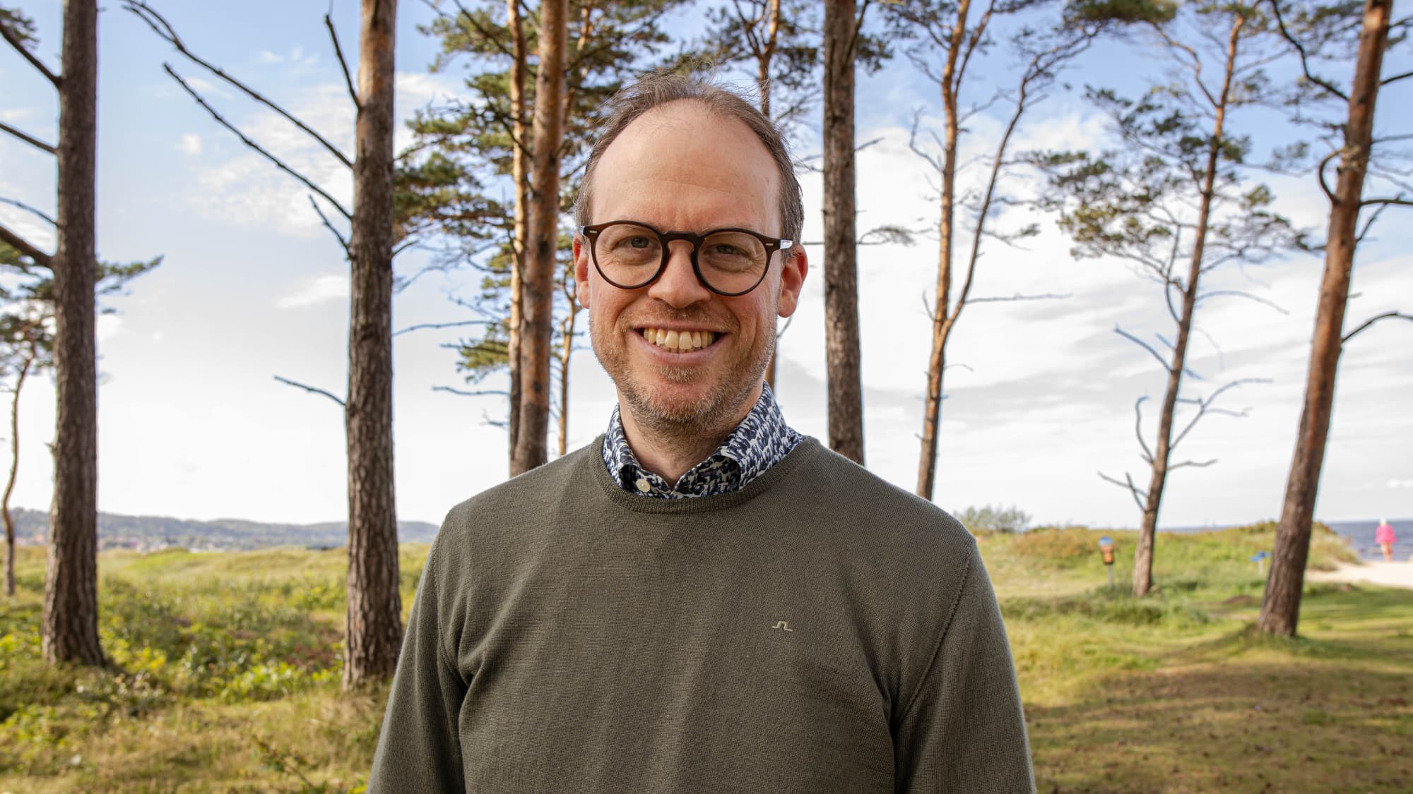 Johan Larsson, vd på Nima står i en skogsglänta och ler mot kameran