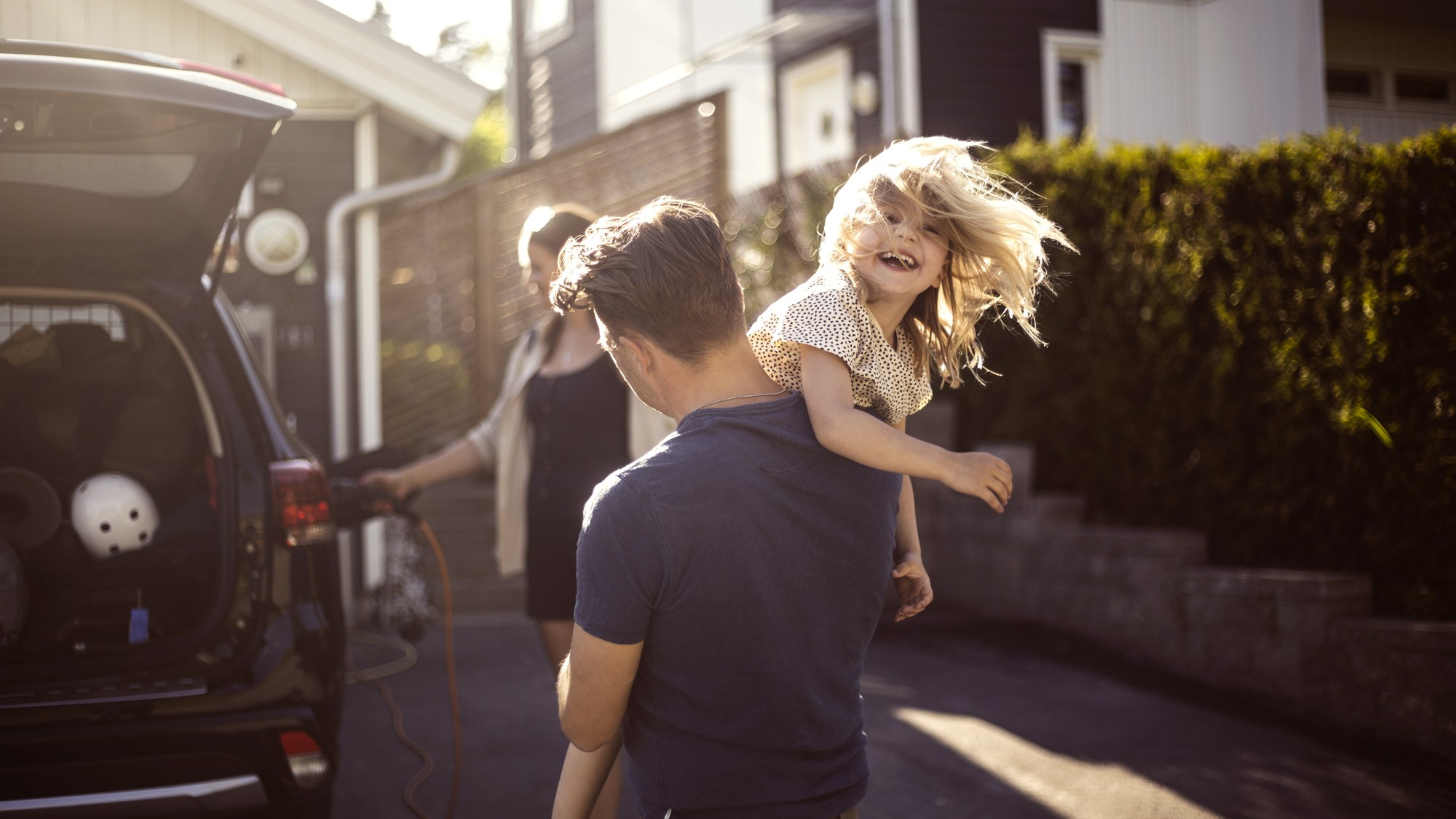 Familj står vid elbil som laddar