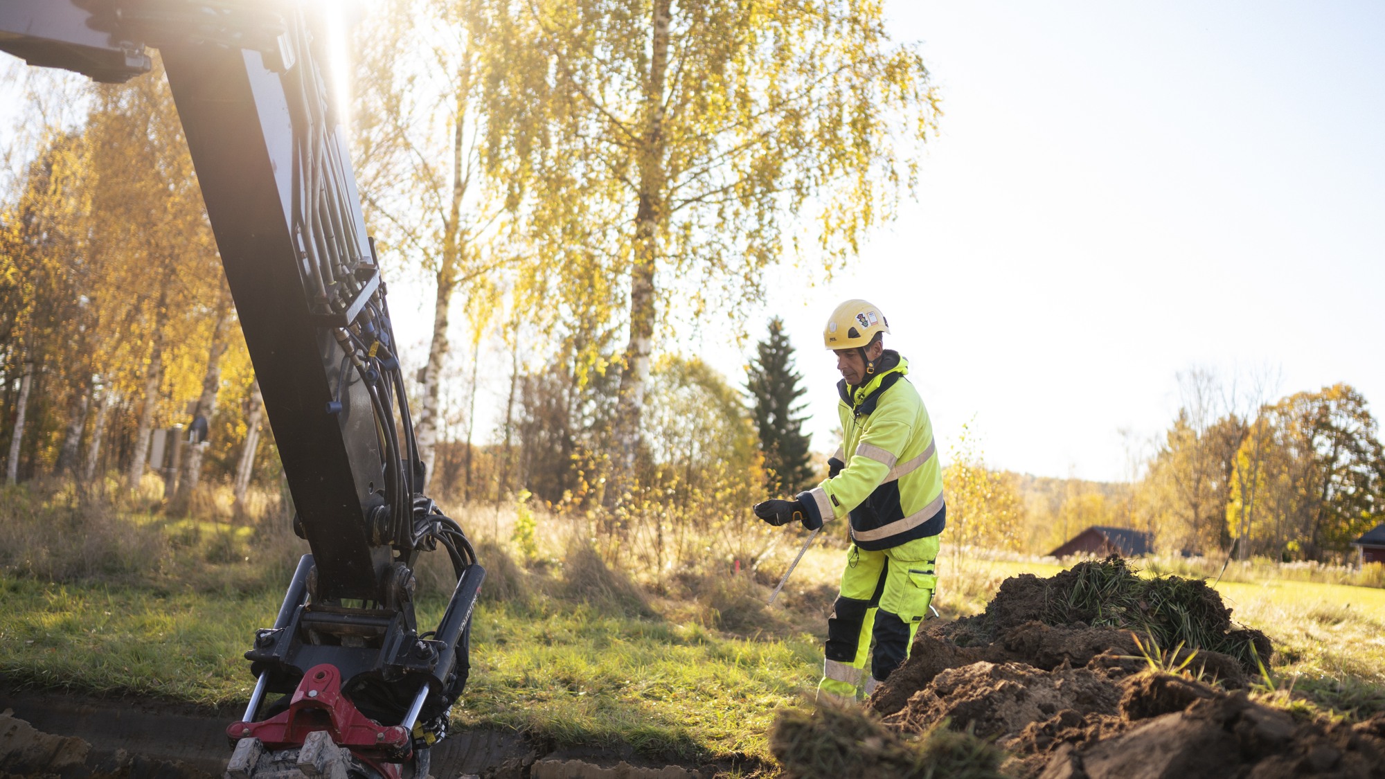 En man i gul skyddsdräkt står bredvid en jordhög.