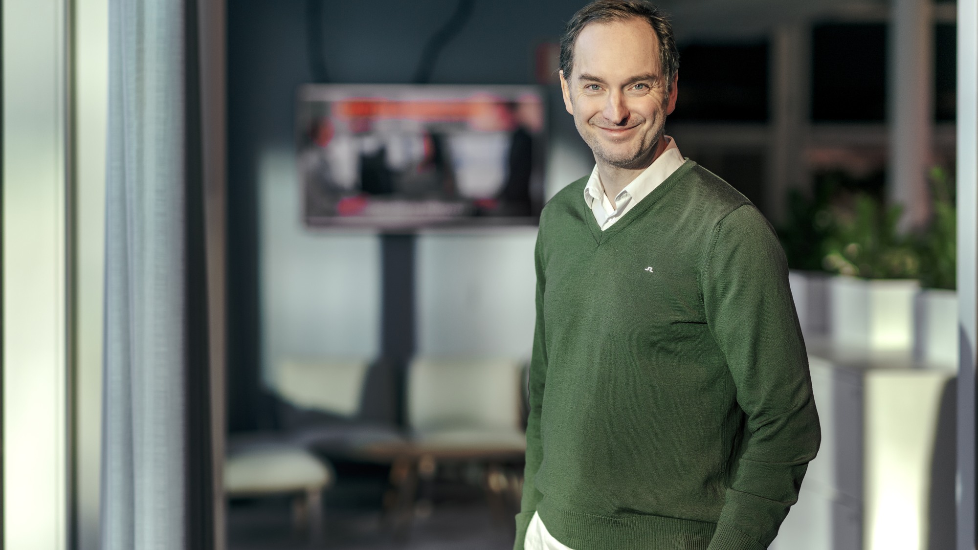 En man klädd i grön tröja och vita byxor.