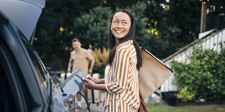 En kvinna i randig klänning tankar bensin i en bil.